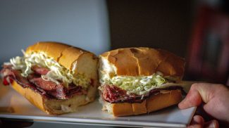 A man holding a fresh roast beef sandwich.