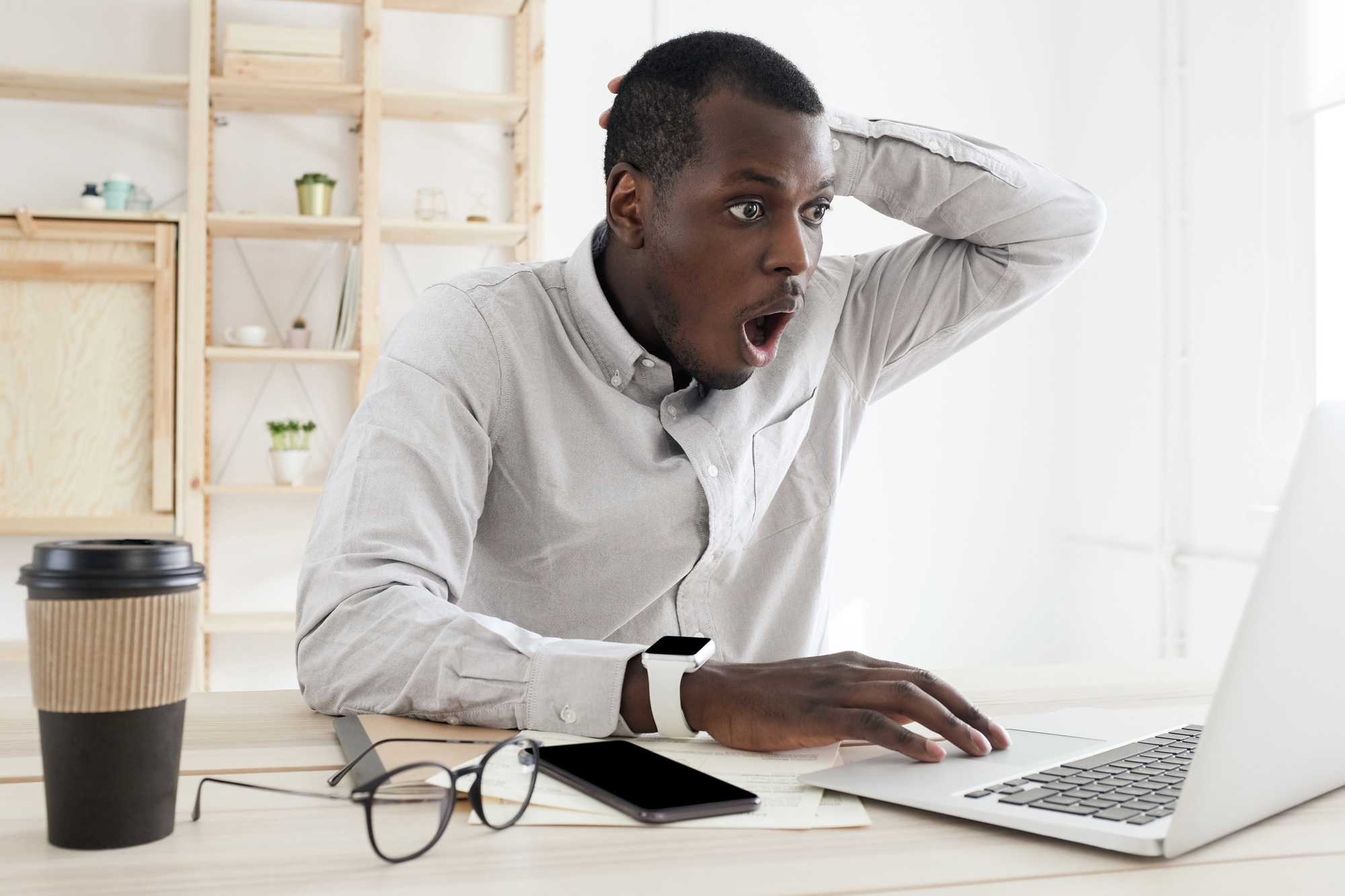 African male having found mistake in calculations and looking desperately at laptop screen