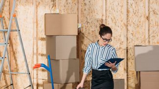 Businesswoman with clipboard checking delivery packages