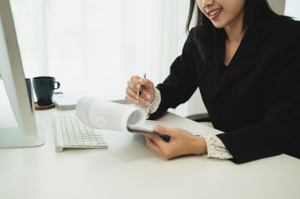 Cropped image o of smiling entrepreneur sales paper reports at modern workplace