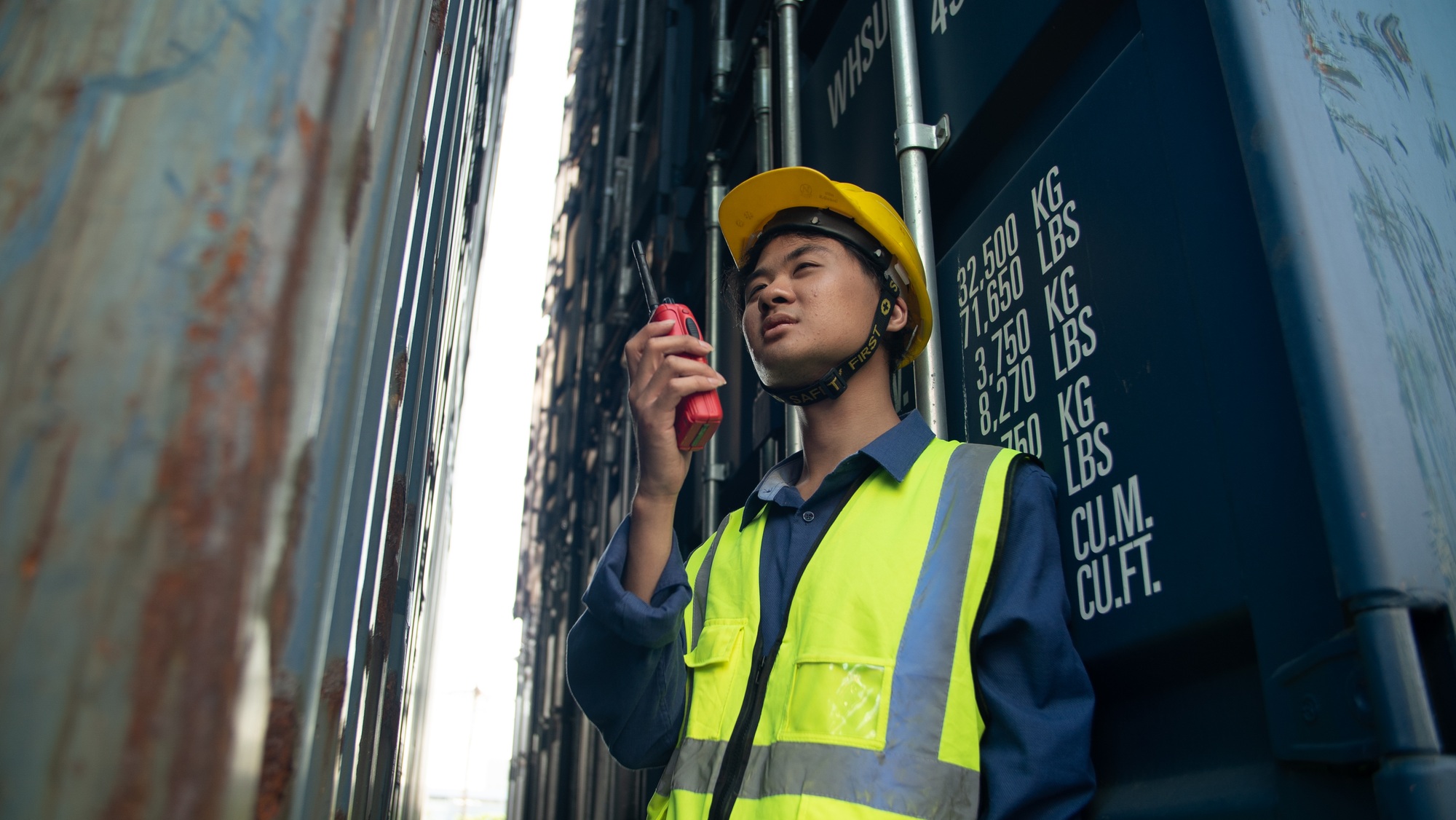 engineer foreman looking upwards towards container shipment for sharing details information