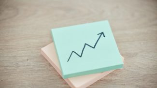 Growth, investment and success with arrow on sticky note for finance, stocks and goal. Price increa