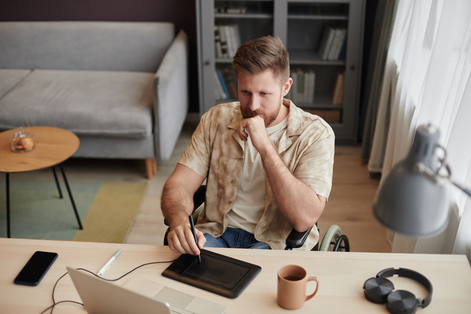 Man with Disability Using Pen Tablet Editing Video at Home Office