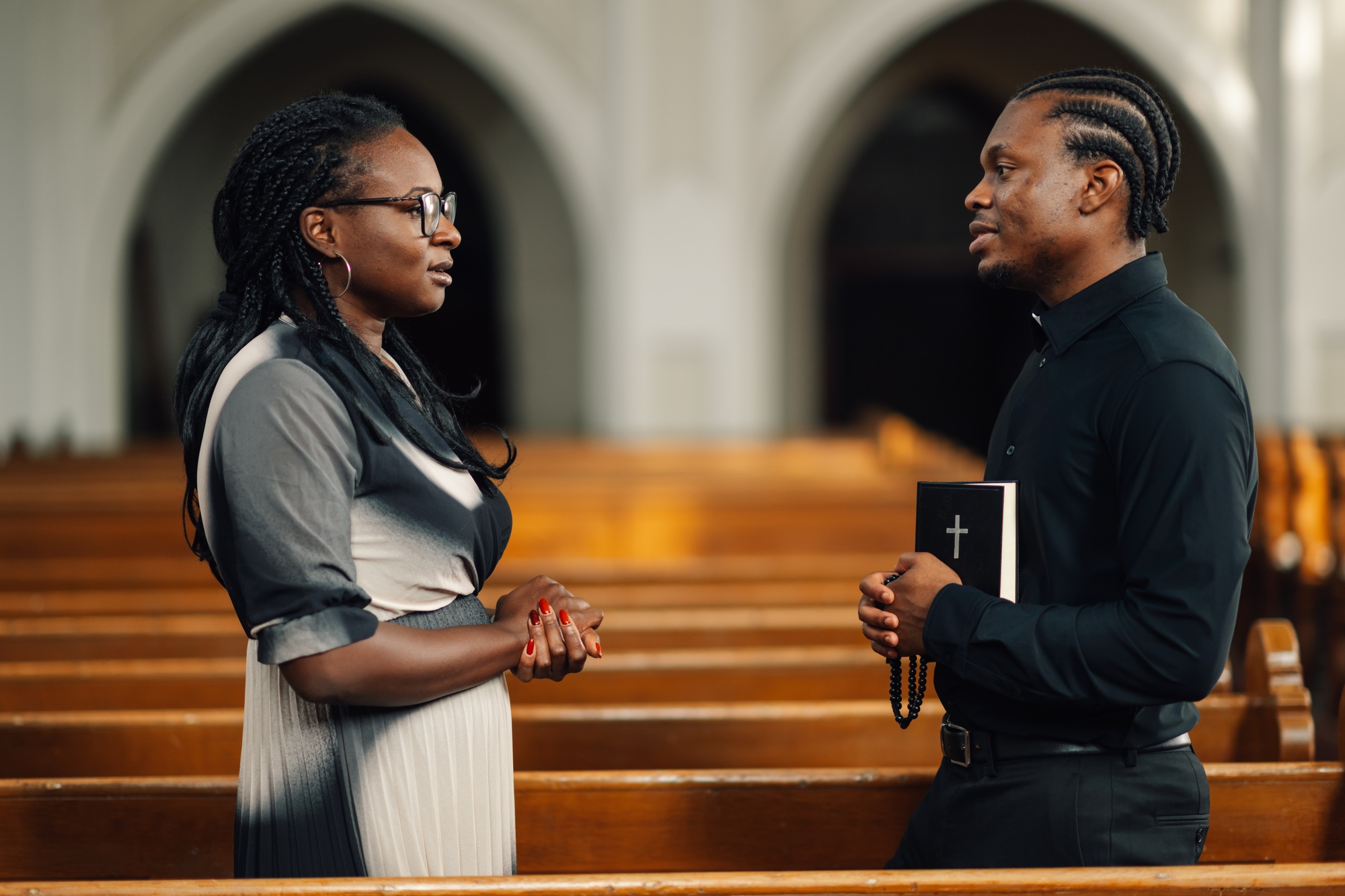 Priest listening to woman talking about her faith in church