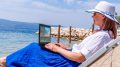 Video blogger, freelancer editing video at beach. Editing Videos On Laptop Using Video Editor App.