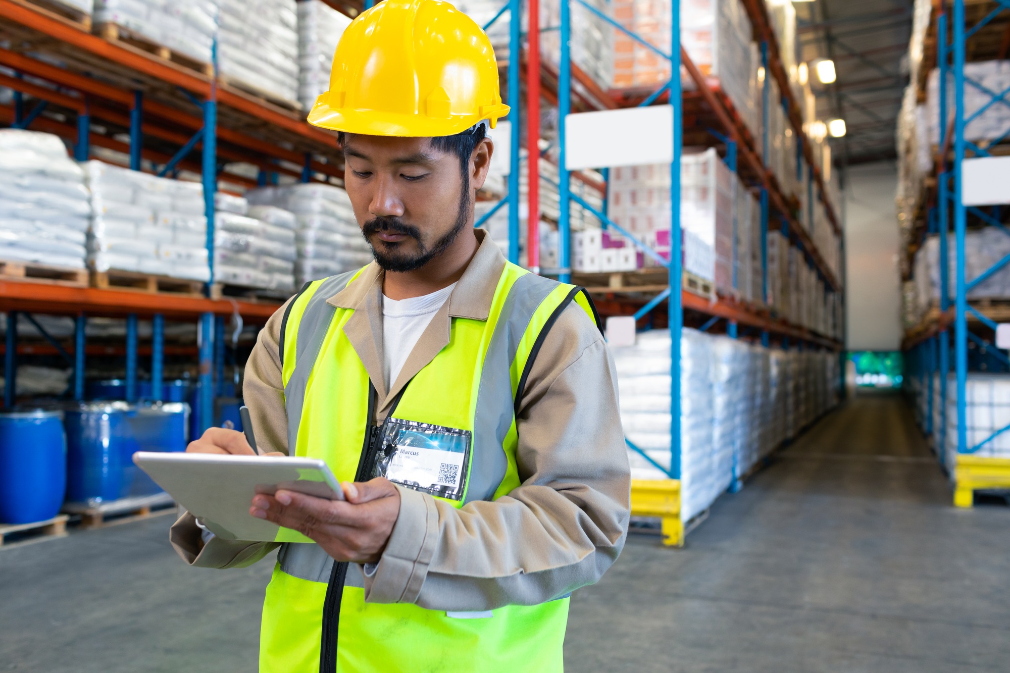 Warehouse worker in safety vest using tablet for inventory management, copy space