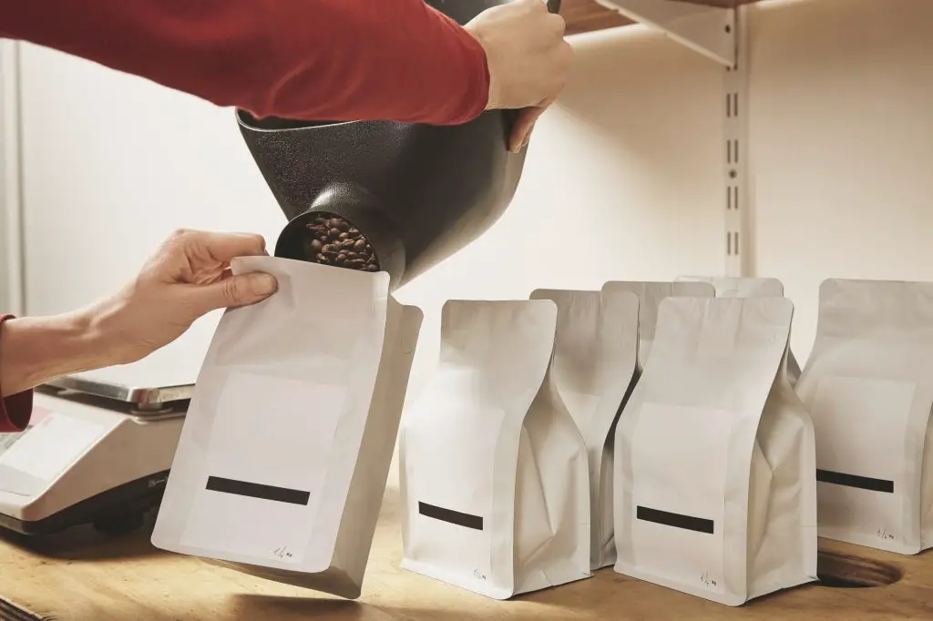 Woman hands fill package with coffee for sale delivery
