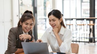 Young Businesswoman Collaborating with Colleague in Modern Office Setting, Discussing Ideas and