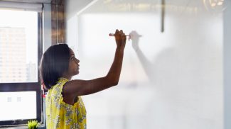 Young woman writing on whiteboard in office environment